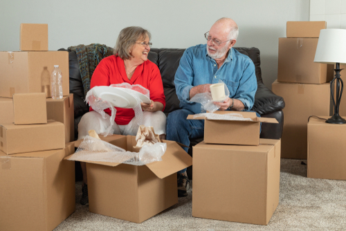 An elderly couple unpacking boxes on a couch.