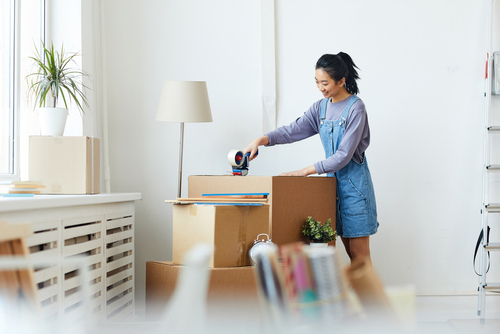 Woman packing boxes in a white room.
